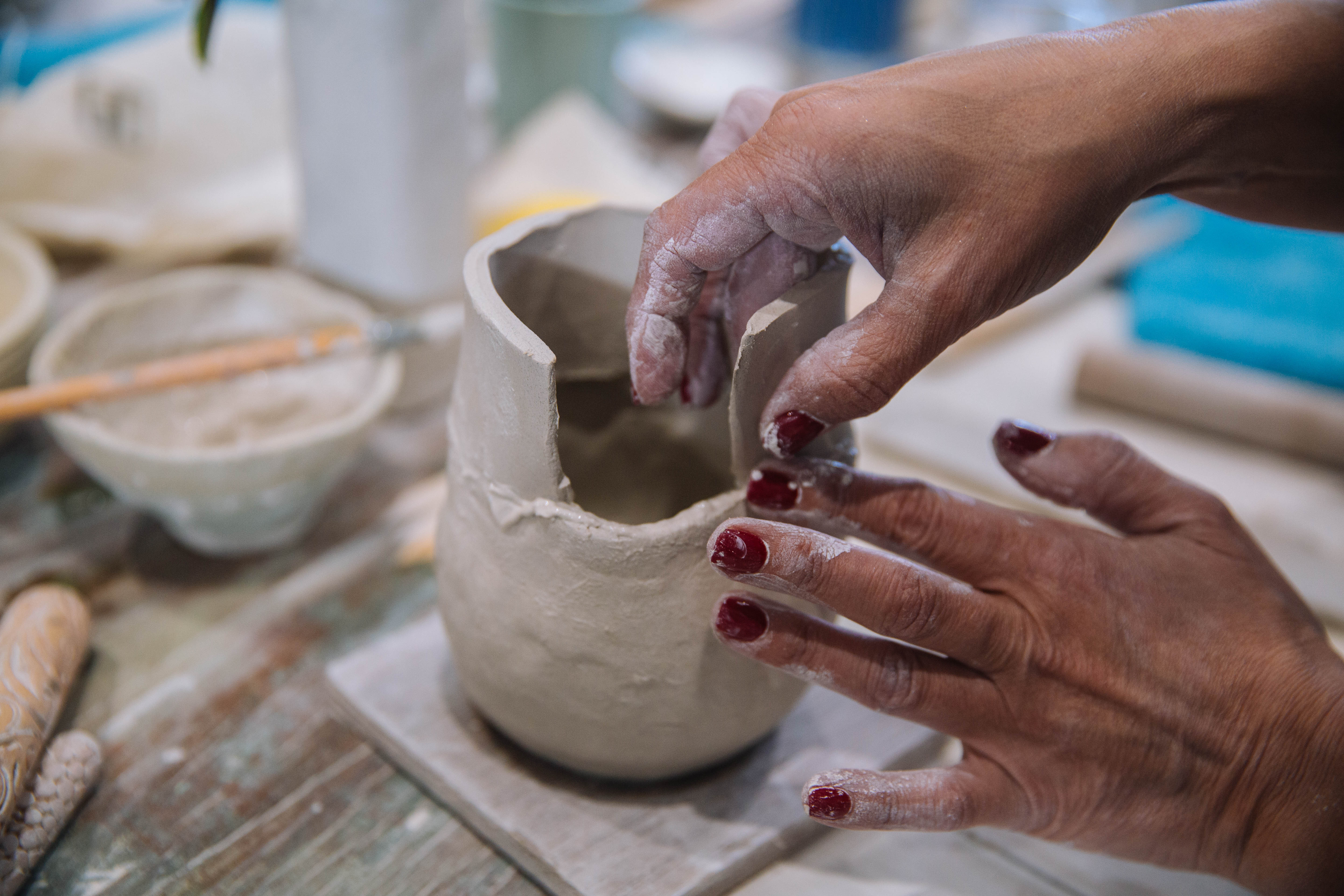 Close up of hands sculpting clay into a small vessel